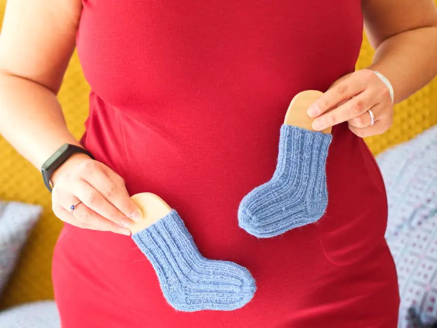 Blaue handgestrickte Babysocken vor Babybauch - Schwanger trotz Endometriose