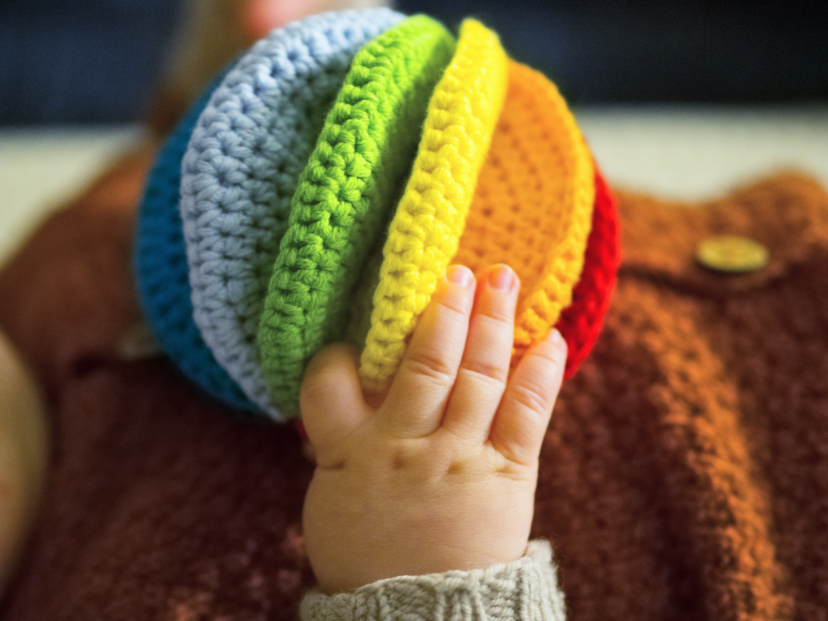 Baby spielt mit selbstgemachtem Greifling aus Wolle